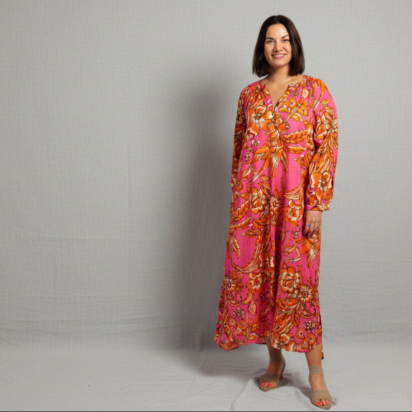 Woman wearing a pink and orange patterned dress against a gray background