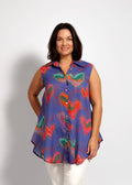 Woman wearing a colorful sleeveless shirt with butterfly design on a white background